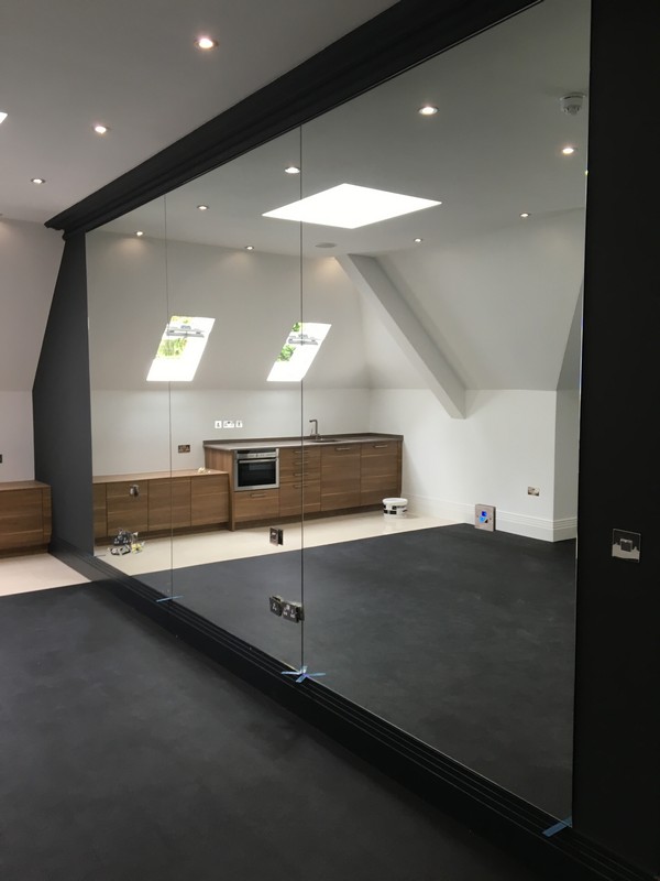 Frameless glass partition in loft conversion by Cobham glaziers